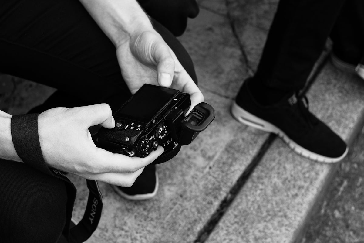 person holding digital camera while sitting