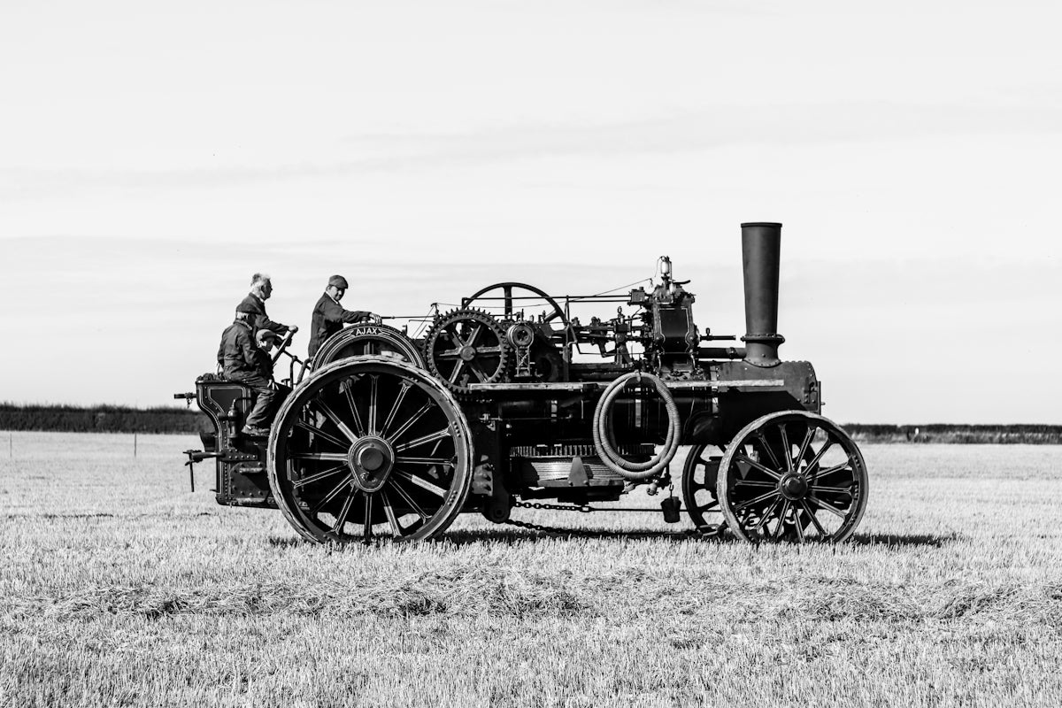 a black and white photo of a man driving a tractor