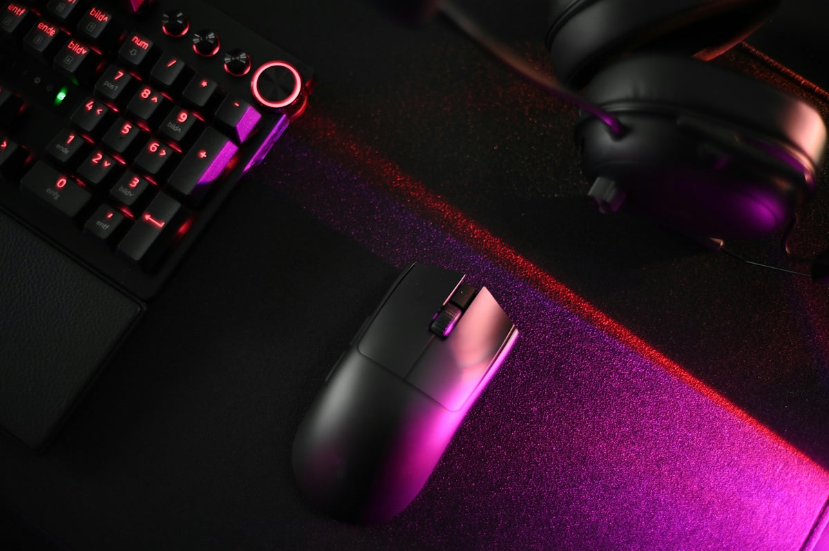 A computer keyboard, mouse, and headphones on a desk
