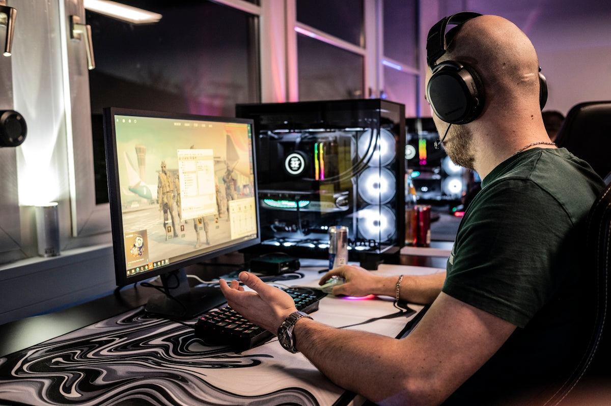 A man sitting in front of a computer monitor wearing headphones