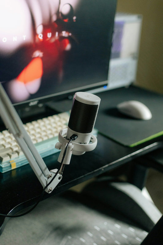 A white microphone on a desk with a computer.