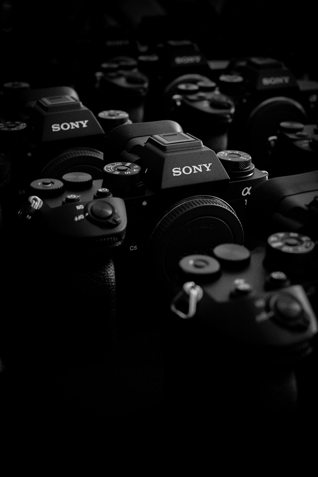 Many black sony cameras are piled together.